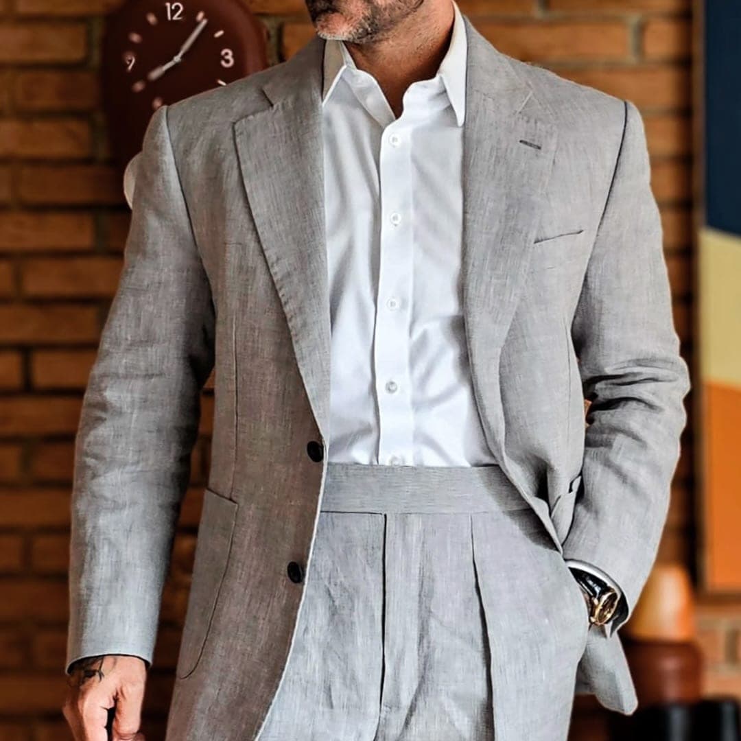 Detalhe de silhueta masculina com terno de alfaiataria napolitana mostrando a proporção clássica de cintura alta e comprimento correto de paletó