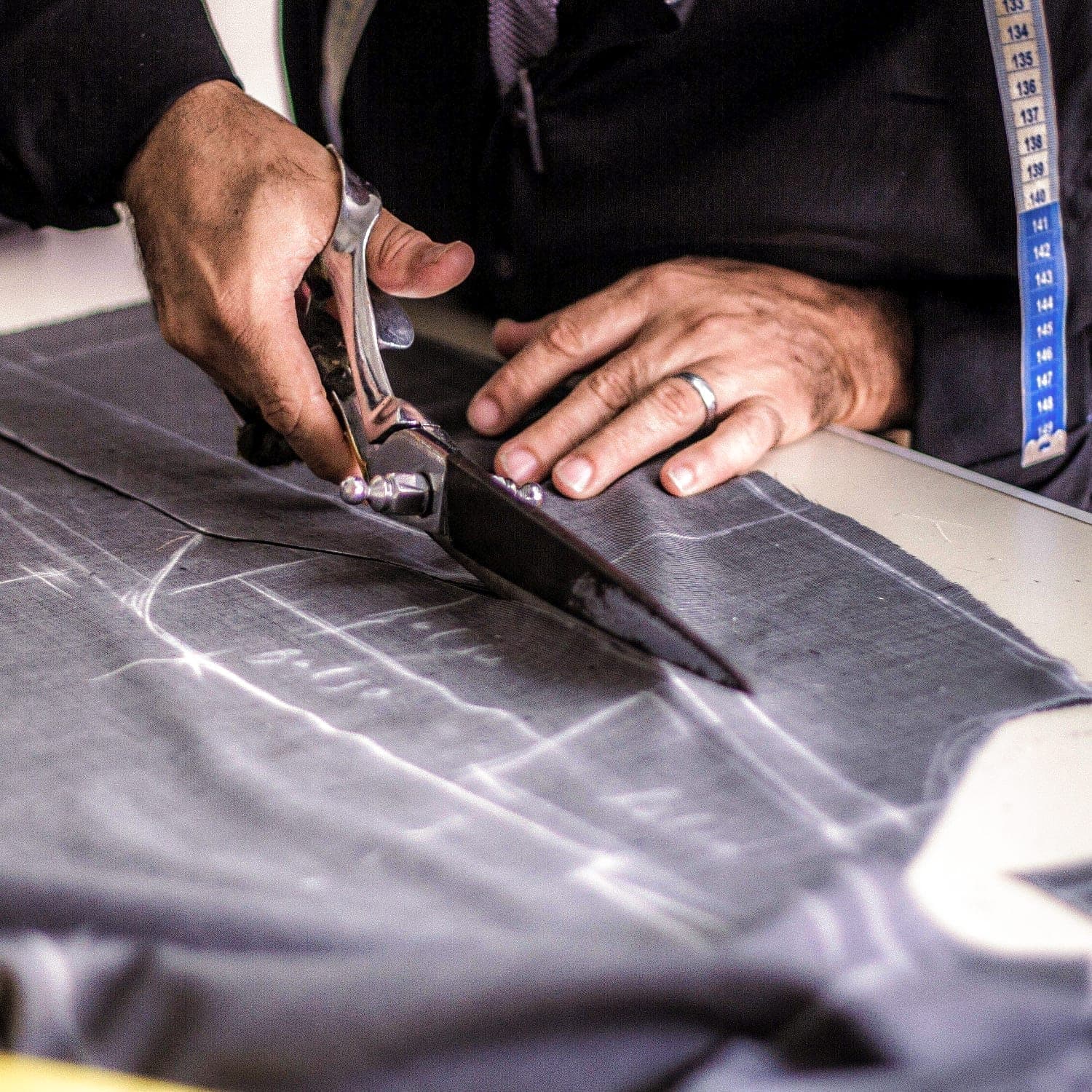 Tailor's hands sewing by hand — the craft that transforms fabric into identity