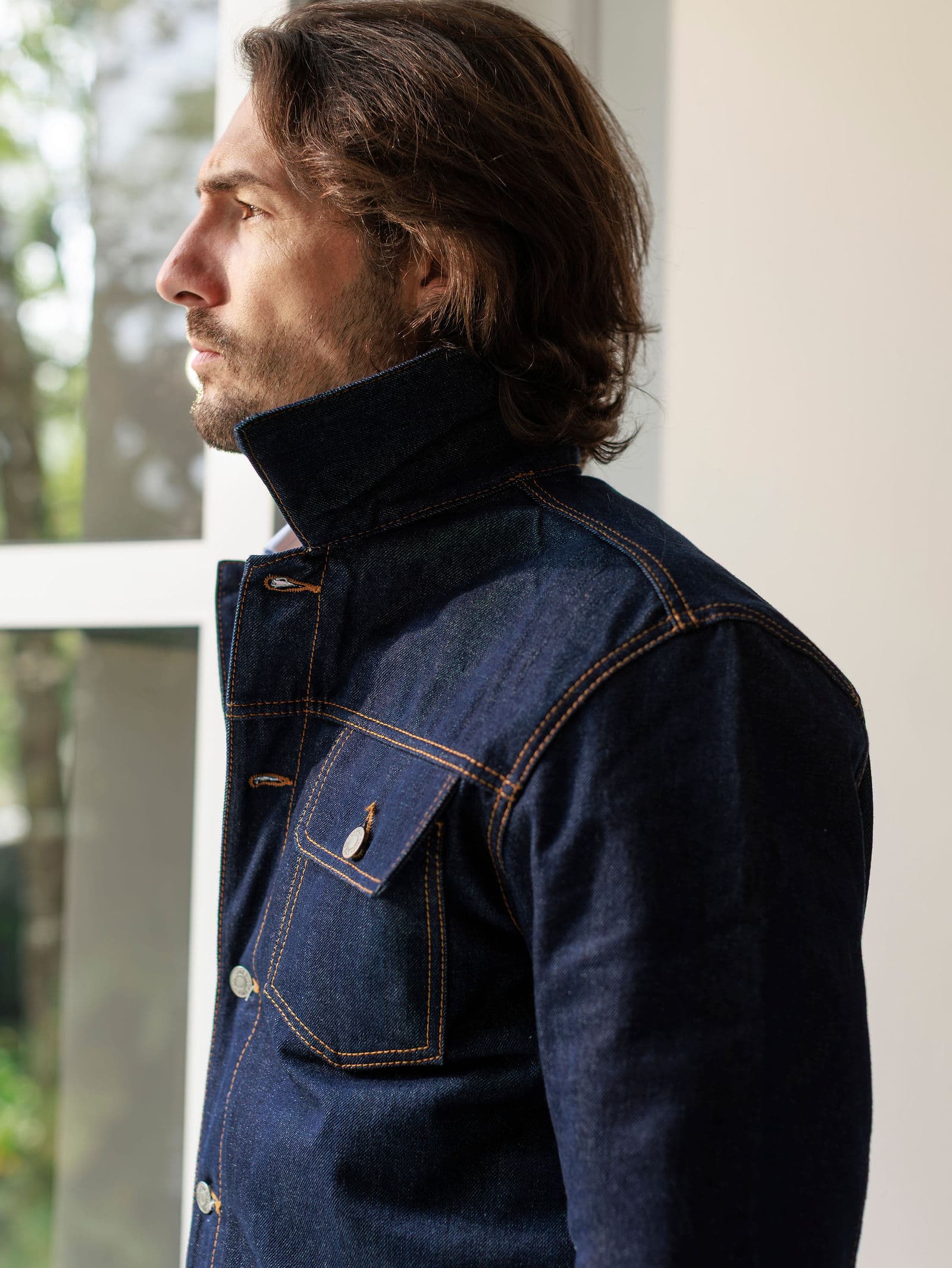 Raw denim trucker with the collar turned up, in profile