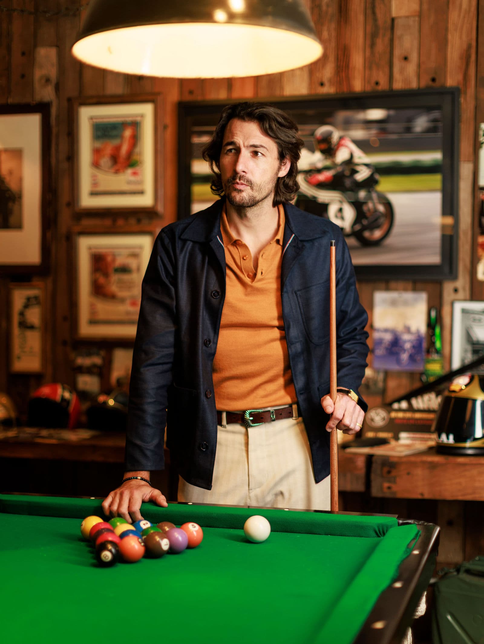 Navy chore coat and orange polo at the billiard table